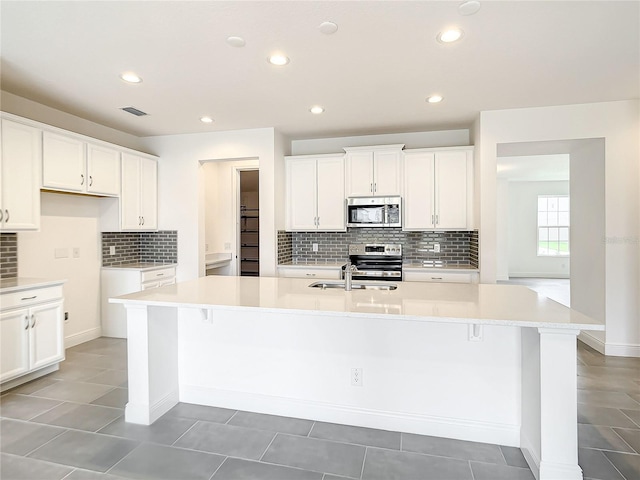 kitchen featuring white cabinets, stainless steel appliances, and a kitchen island with sink