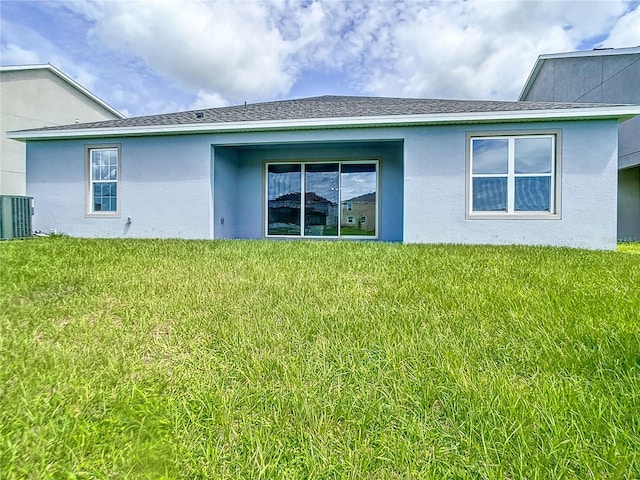 back of property featuring central AC unit and a yard