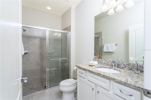 bathroom with tile floors, a shower with door, a textured ceiling, toilet, and large vanity