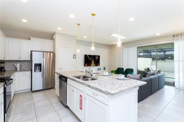 kitchen featuring stainless steel appliances, a center island with sink, sink, white cabinets, and light stone counters