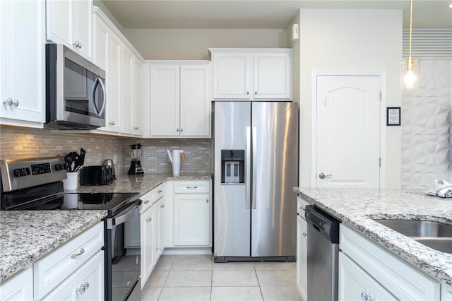 kitchen featuring white cabinetry, appliances with stainless steel finishes, light tile floors, and light stone counters