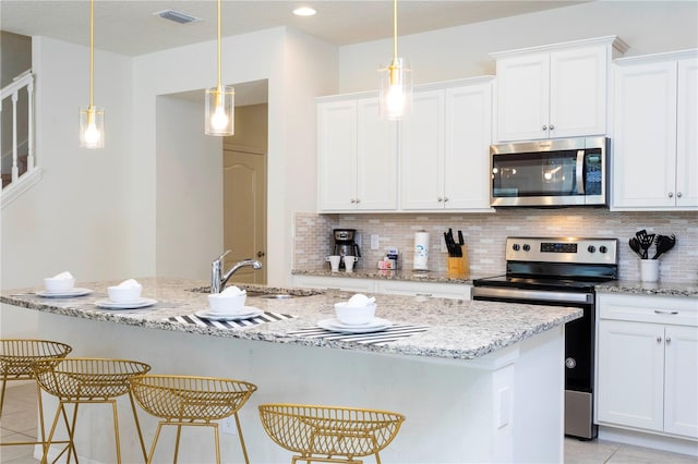 kitchen featuring tasteful backsplash, stainless steel appliances, a kitchen island with sink, and white cabinetry