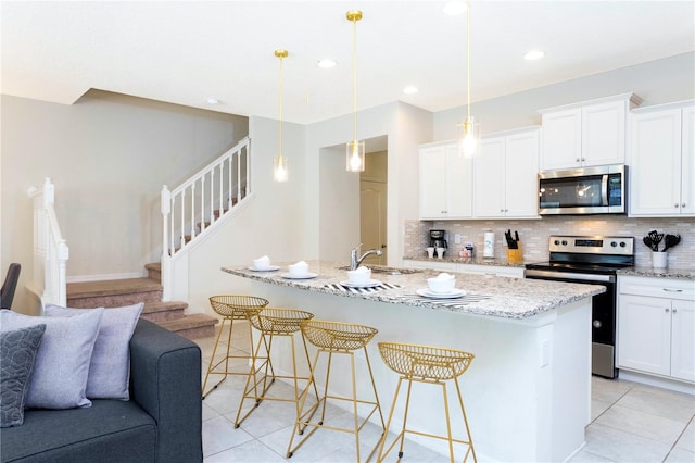 kitchen with an island with sink, stainless steel appliances, tasteful backsplash, and light stone countertops