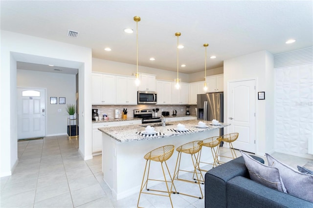 kitchen featuring backsplash, white cabinetry, appliances with stainless steel finishes, and light stone countertops