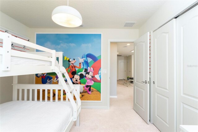 bedroom featuring a closet, a textured ceiling, and light colored carpet