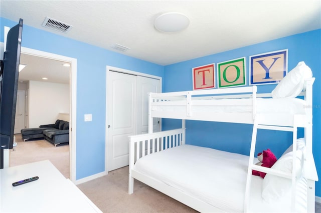 bedroom featuring light carpet, a closet, and a textured ceiling