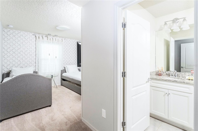 bathroom with a textured ceiling, tile flooring, and vanity with extensive cabinet space