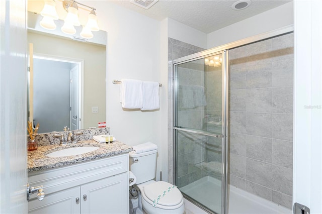 bathroom featuring walk in shower, a textured ceiling, oversized vanity, and toilet