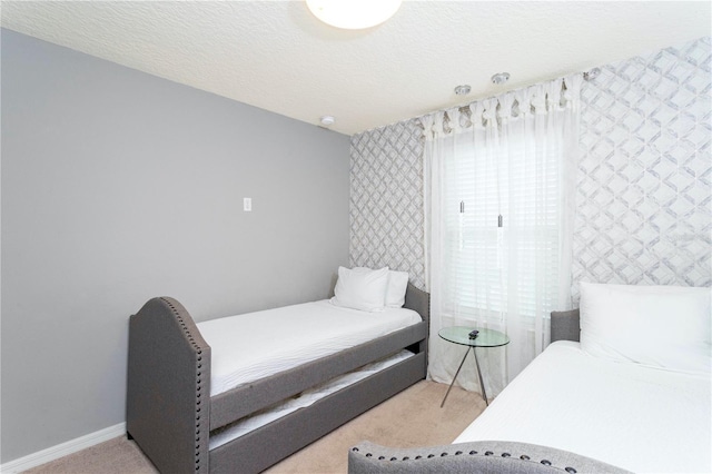 bedroom with light colored carpet and a textured ceiling