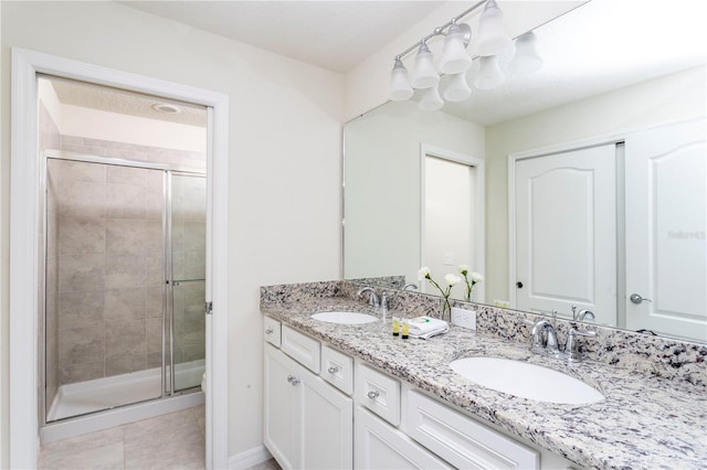 bathroom featuring tile floors, vanity with extensive cabinet space, double sink, and an enclosed shower