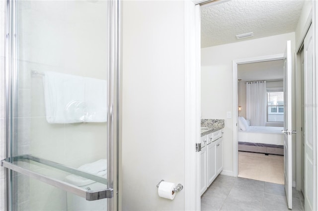 bathroom with a textured ceiling, vanity, and tile flooring