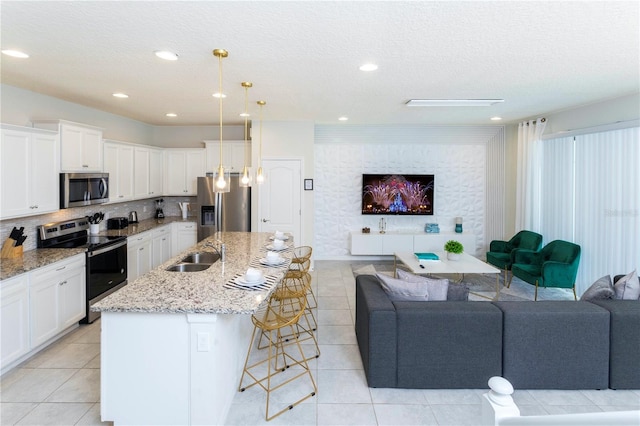 kitchen featuring appliances with stainless steel finishes, light tile floors, white cabinets, light stone counters, and pendant lighting