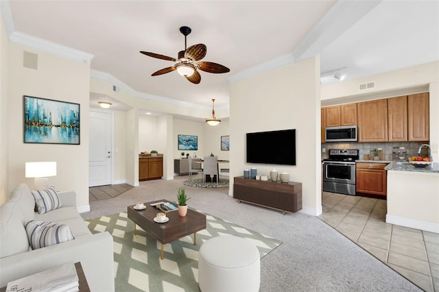 living room with ceiling fan, crown molding, and light carpet