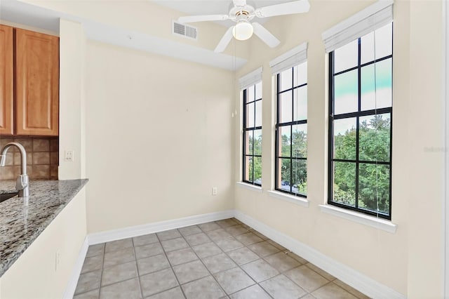 unfurnished dining area featuring ceiling fan, light tile patterned flooring, and sink