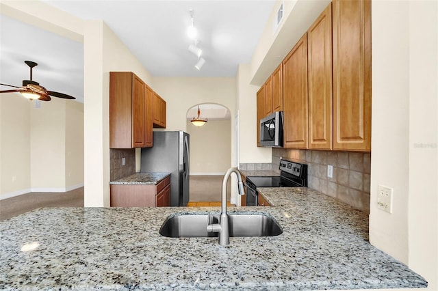 kitchen with tasteful backsplash, light stone countertops, sink, and appliances with stainless steel finishes