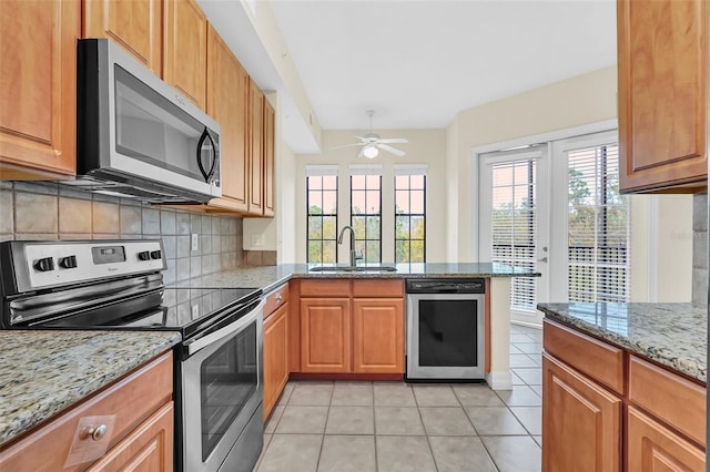 kitchen with sink, ceiling fan, light tile patterned floors, appliances with stainless steel finishes, and light stone counters