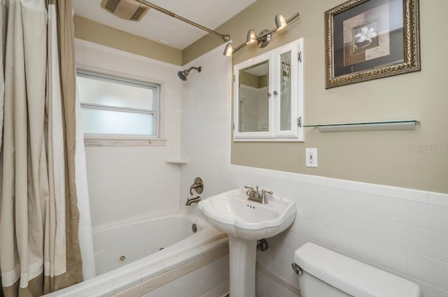 bathroom with toilet, shower / bathtub combination with curtain, and tile walls