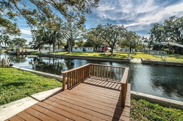 view of dock with a water view and a yard