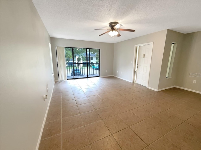 empty room featuring ceiling fan, light tile patterned floors, and a textured ceiling