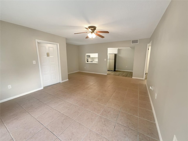 tiled empty room featuring ceiling fan