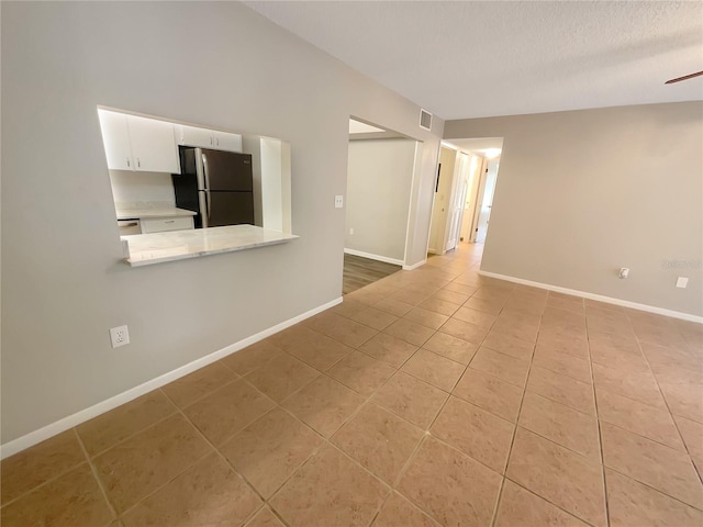 empty room featuring light tile patterned floors, a textured ceiling, and ceiling fan