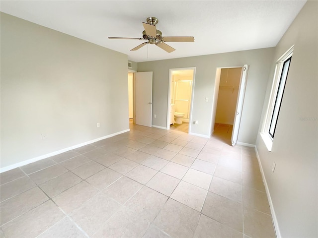 unfurnished bedroom featuring ceiling fan, a spacious closet, multiple windows, connected bathroom, and a closet