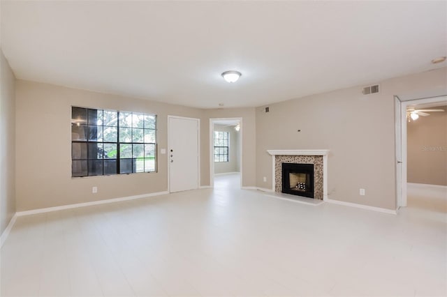 unfurnished living room with a tiled fireplace, ceiling fan, and hardwood / wood-style floors