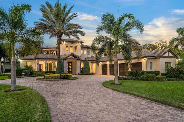 6109 Orta Ct, Windermere, FL 34786 - mediterranean / spanish home with curved driveway, a yard, stucco siding, and an attached garage