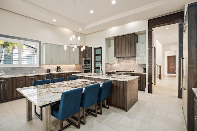 kitchen with a kitchen island, a kitchen bar, light tile patterned floors, light stone counters, and tasteful backsplash