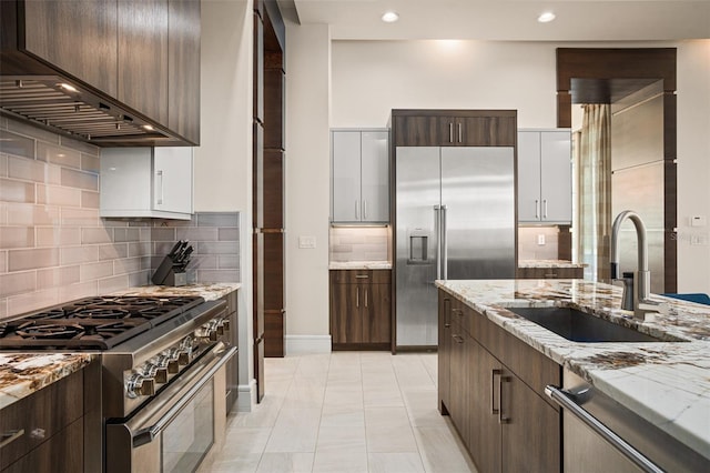 6109 Orta Ct, Windermere, FL 34786 - kitchen featuring high end appliances, custom exhaust hood, a sink, backsplash, and light stone countertops