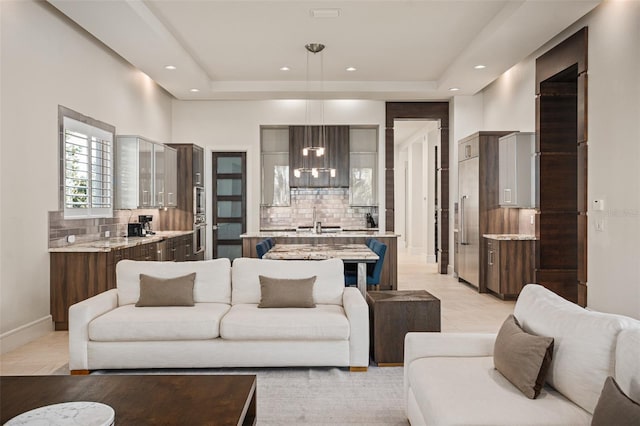 living room with sink, light tile patterned flooring, and a tray ceiling