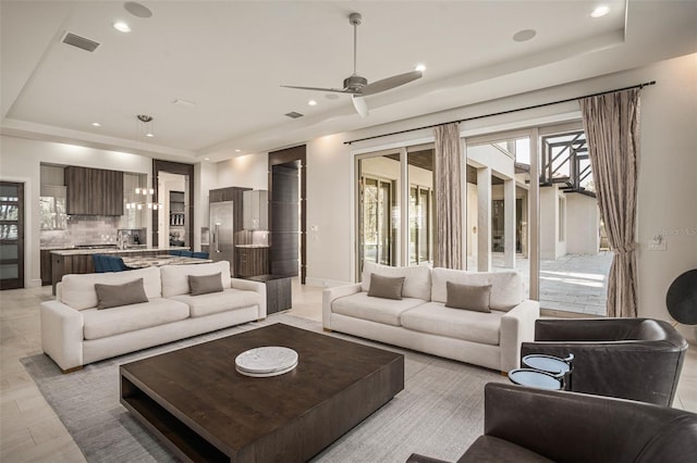 living room with ceiling fan and a tray ceiling