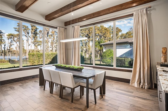 sunroom / solarium with a water view, beamed ceiling, and a wealth of natural light