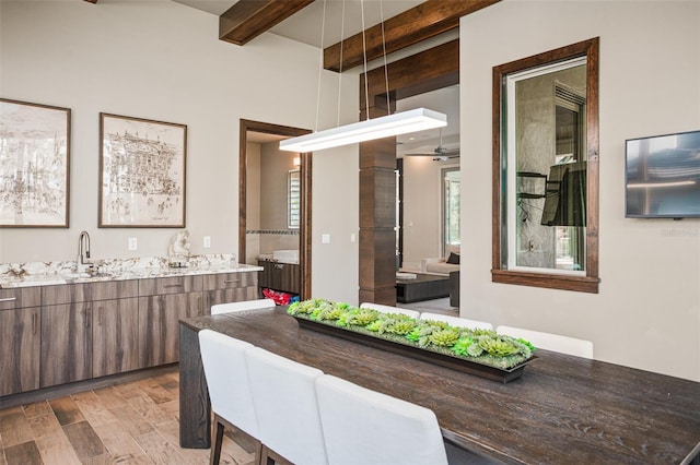 interior space with beam ceiling, sink, light wood-type flooring, and ceiling fan