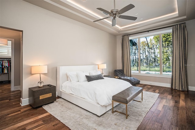 bedroom featuring dark hardwood / wood-style floors, a tray ceiling, and ceiling fan