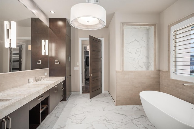 bathroom with tile walls, vanity, and a bathing tub