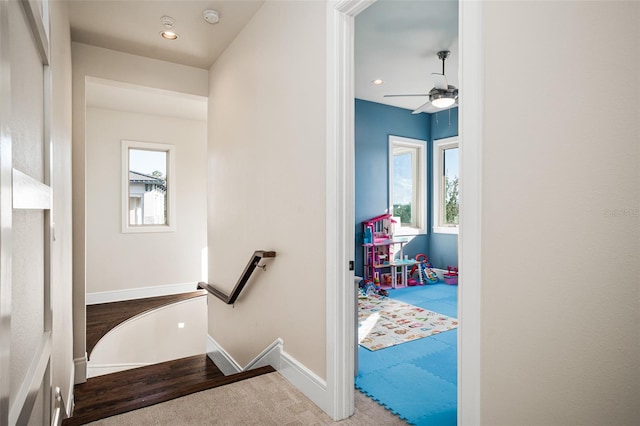 stairs featuring hardwood / wood-style floors, ceiling fan, and a wealth of natural light