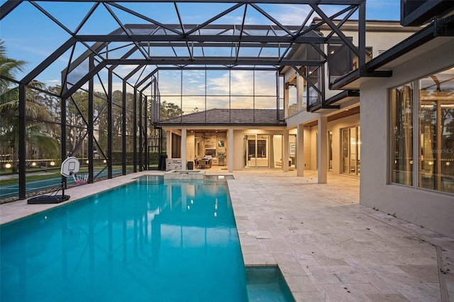 pool at dusk with a patio area and a lanai