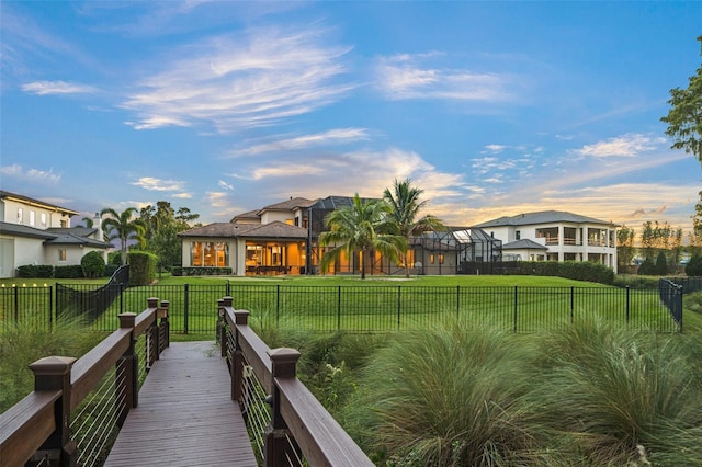 rear view of property with a lawn and glass enclosure