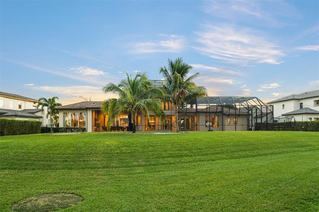 rear view of house featuring a lanai and a yard