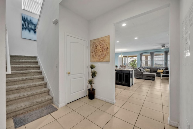 tiled foyer featuring ceiling fan with notable chandelier