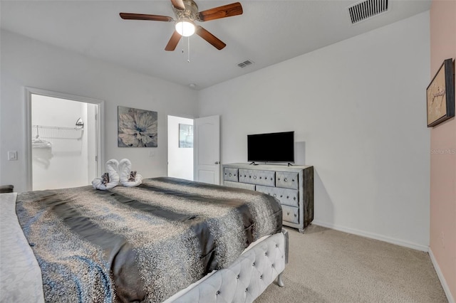 bedroom featuring a spacious closet, ceiling fan, a closet, and light carpet