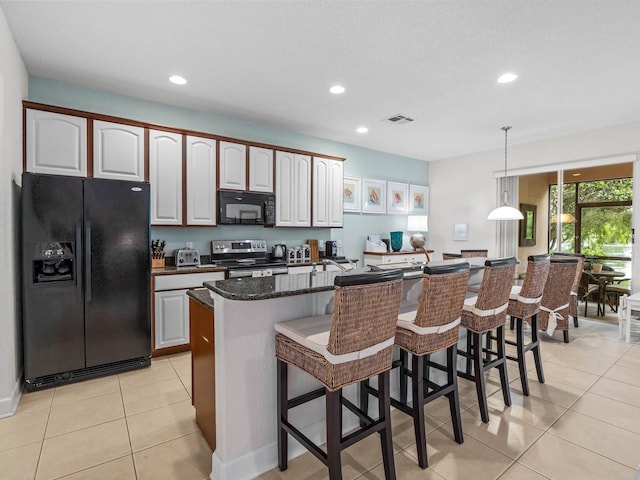 kitchen featuring a center island, light tile patterned floors, a kitchen breakfast bar, white cabinets, and black appliances