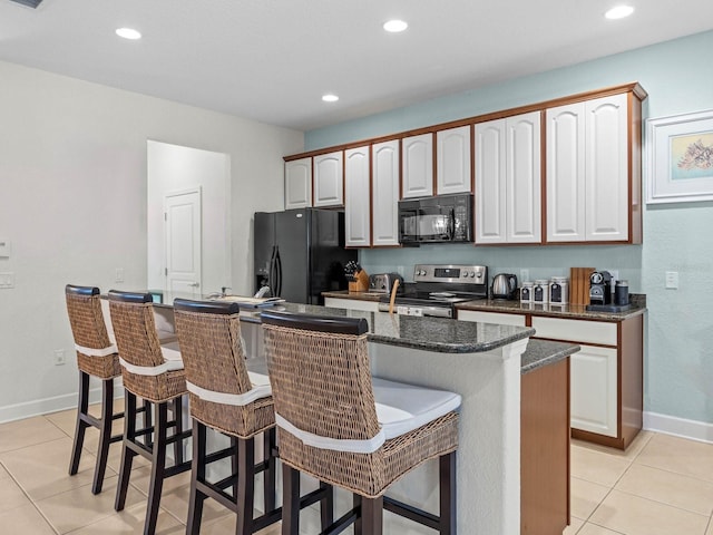 kitchen with a kitchen breakfast bar, light tile patterned flooring, an island with sink, and black appliances