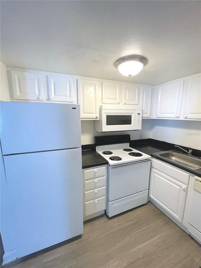 kitchen featuring white appliances, sink, white cabinetry, and light wood-type flooring