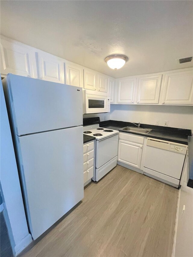 kitchen with white appliances, sink, white cabinets, and light wood-type flooring