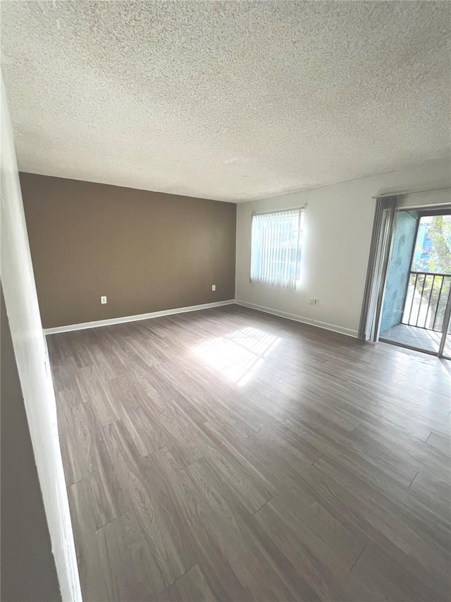 unfurnished room with hardwood / wood-style flooring and a textured ceiling