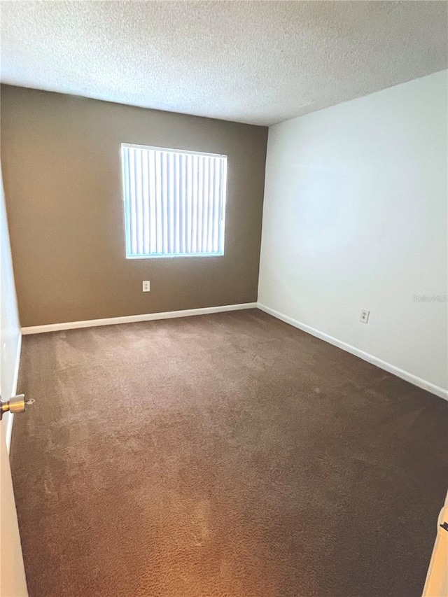 unfurnished room with dark colored carpet and a textured ceiling