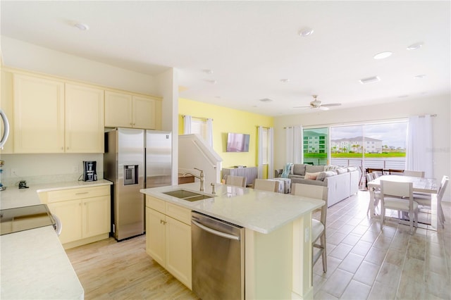 kitchen featuring light hardwood / wood-style flooring, a kitchen island with sink, ceiling fan, stainless steel appliances, and sink