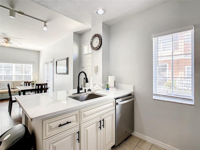 kitchen featuring stainless steel dishwasher, sink, kitchen peninsula, and track lighting